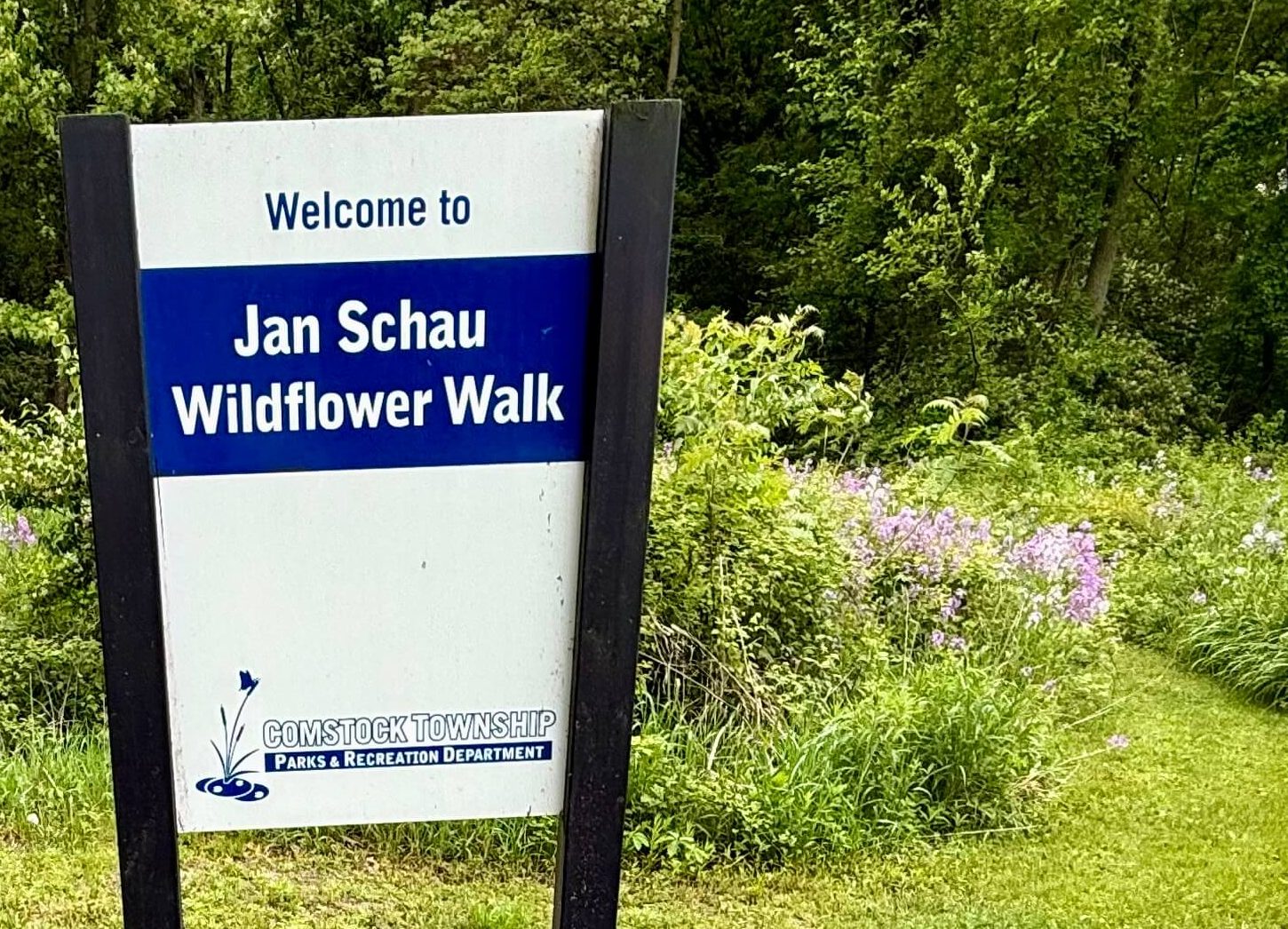 Welcome to Jan Schau Wildflower Walk sign in front of grassy trail